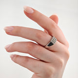 Hand mit quadratischem Silberring und Diamantmuster auf mittlerem Finger vor weißem Hintergrund