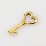 Kleiner goldener Schlüssel mit herzförmigem Griff auf weißem Hintergrund.