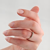 Linke Hand mit nudefarben lackierten Nägeln und silbernem Ring mit Diamanten.