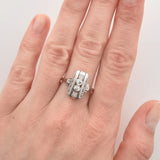 Linke Hand mit Silberring auf dem Mittelfinger, der zwei kleine runde Diamanten und ein geometrisches Design aufweist.