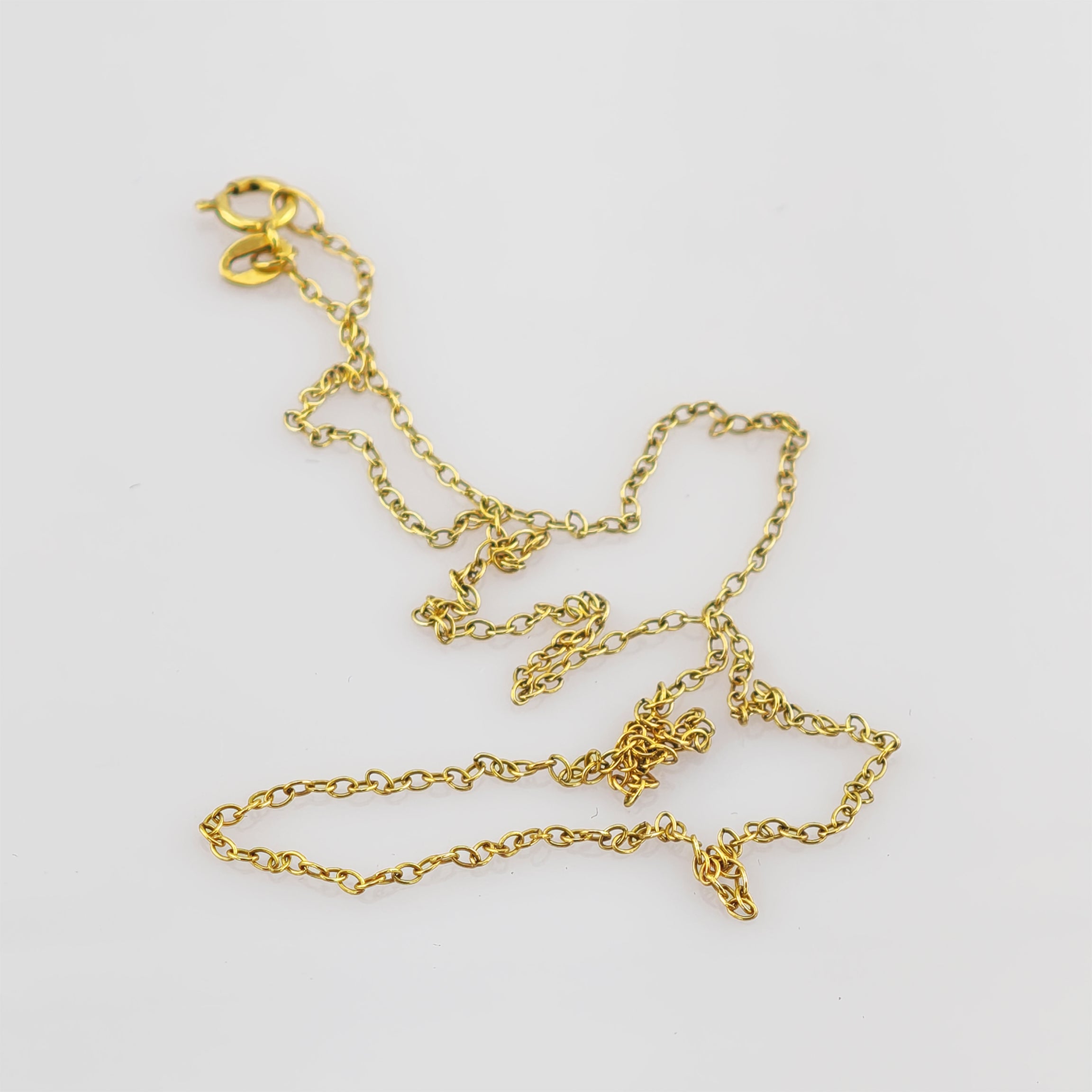 Lose Goldkette mit kleinen ovalen Gliedern auf weißem Hintergrund