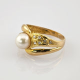 Luxuriöser goldener Ring mit großem weißen Perlmittelstück und sechs kleinen Diamanten auf einem blattförmigen Bandabschnitt.