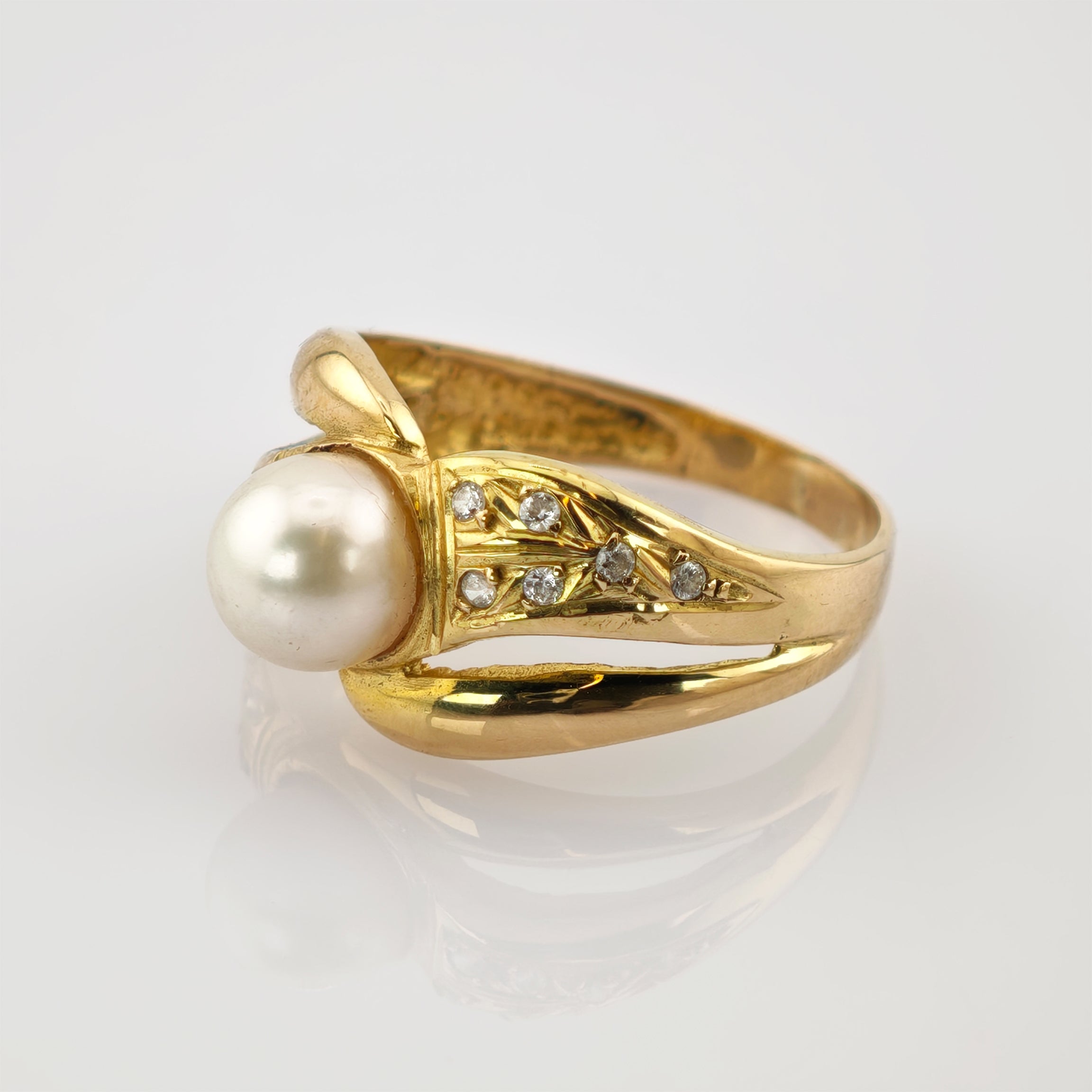 Luxuriöser goldener Ring mit großem weißen Perlmittelstück und sechs kleinen Diamanten auf einem blattförmigen Bandabschnitt.