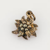 Kleiner Metallanhänger in Form einer stilisierten Blume mit acht texturierten Blättern und schwarz-goldener Patina.