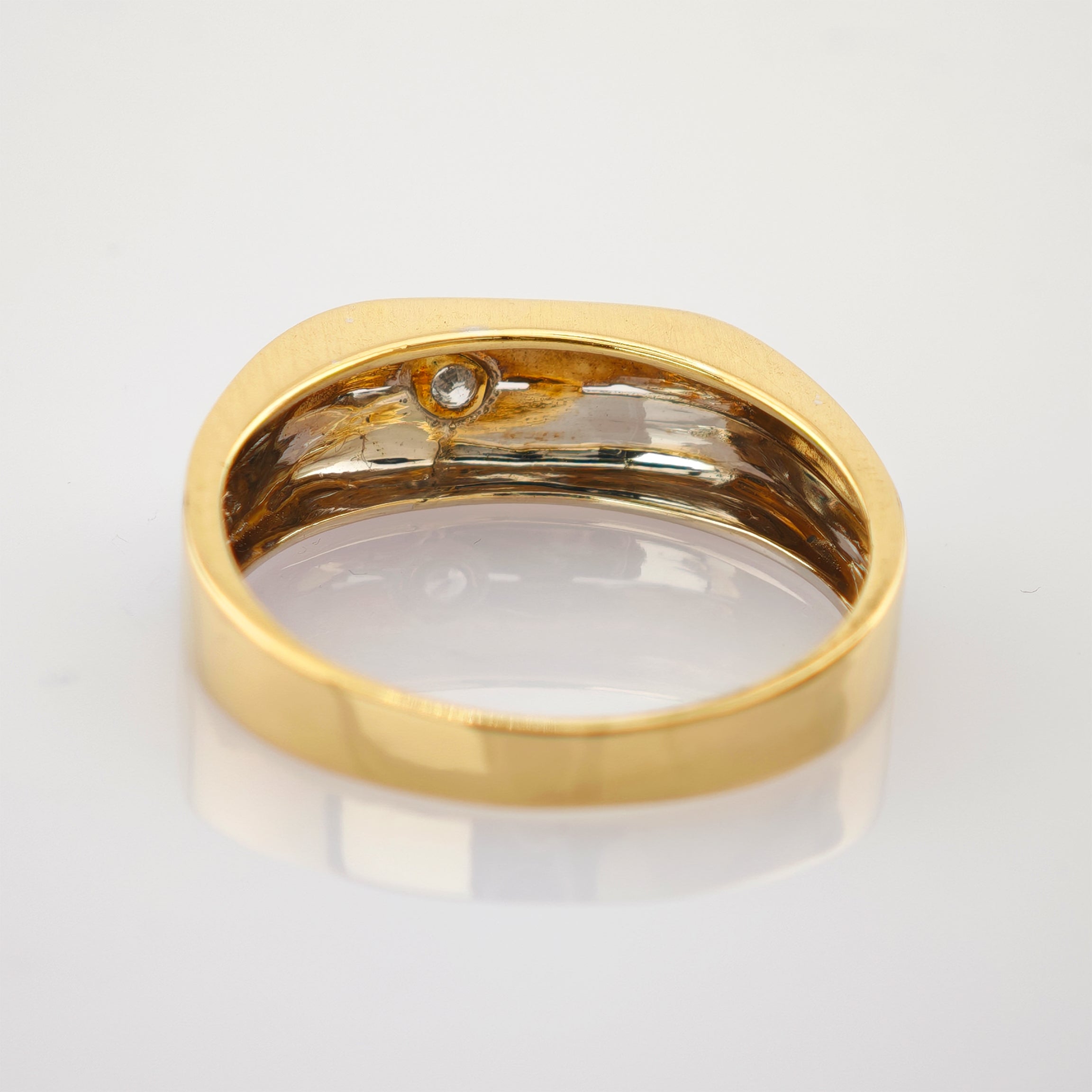 Nahaufnahme eines glänzenden Gelbgoldrings mit spiegelnder, leicht angelaufener Innenfläche und kleinem Kreisdetaill.