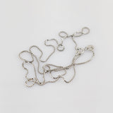 Nahaufnahme einer verhedderten silbernen Halskette mit rechteckigen Gliedern und Karabinerverschluss vor weißem Hintergrund