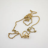 Nahaufnahme einer verhedderten goldenen Halskette mit glänzenden, verdrehten Gliedern auf weißem Hintergrund