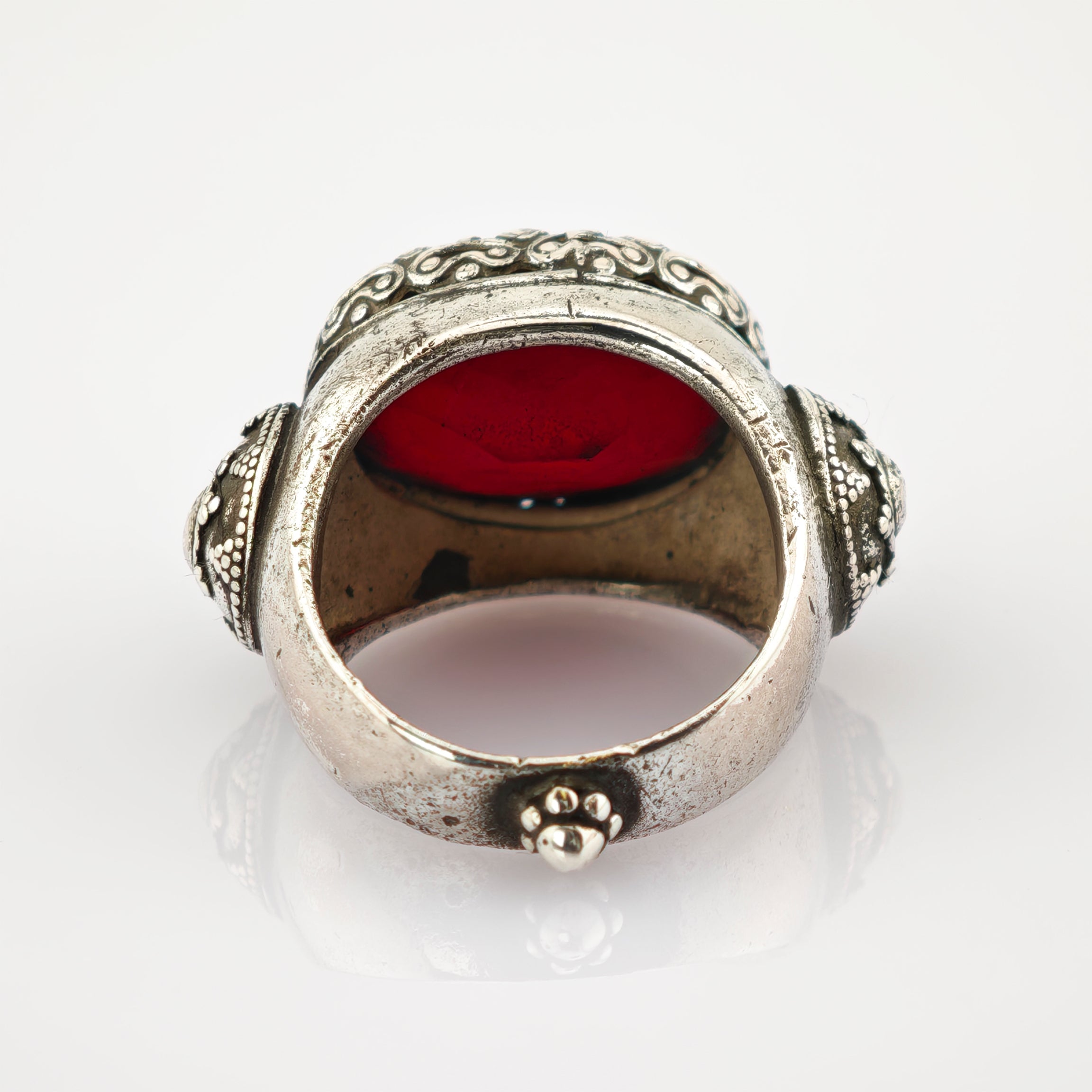Ornamentaler Silberring mit eingravierten Mustern und großem roten Stein, floral verzierte Seiten.
