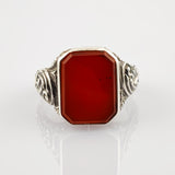 Ornamentierter silberner Ring mit rechteckigem rotem Edelstein und Gravuren