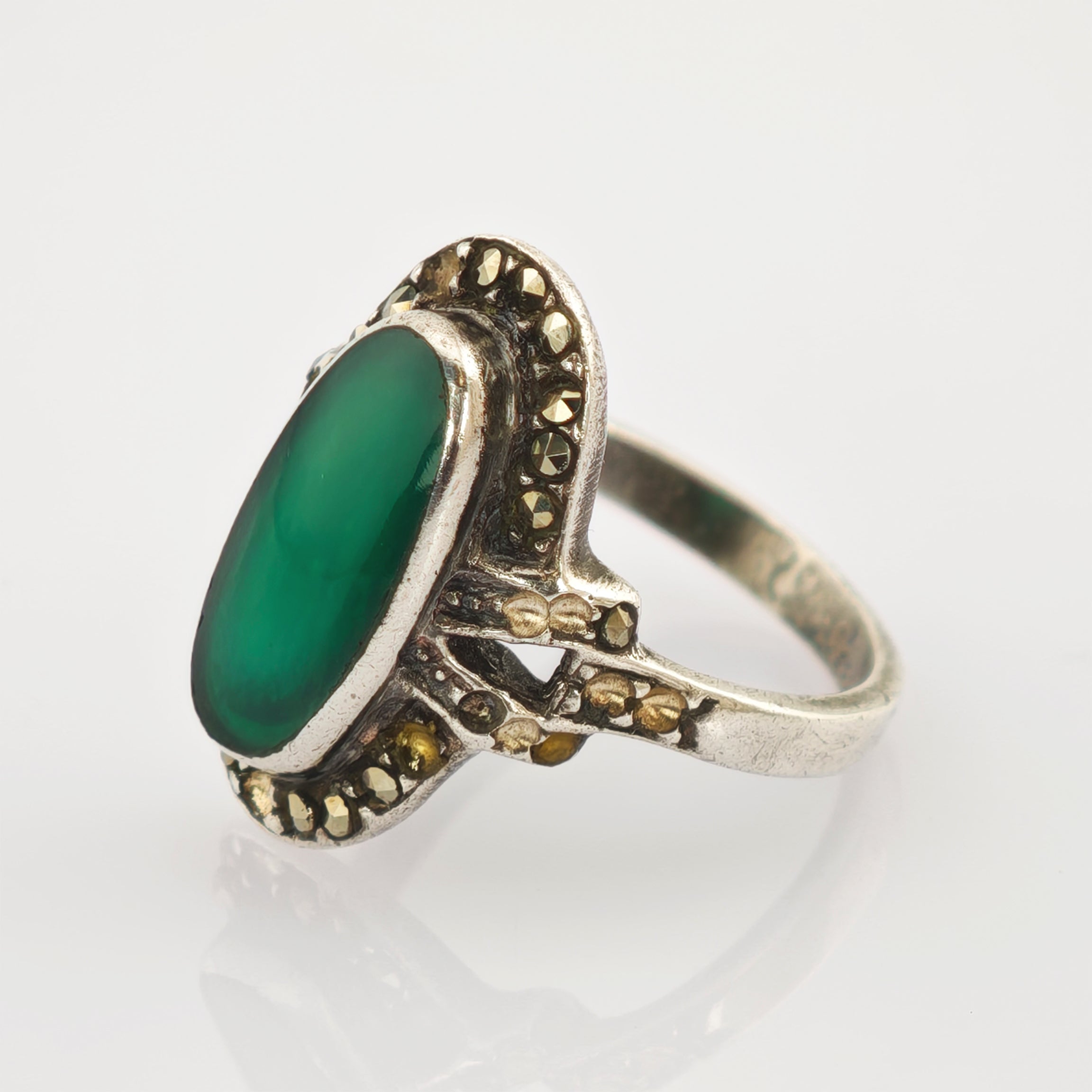 Ornater Vintage-Silberring mit großem ovalem grünen Stein und kleinen Gold-Silber-Verzierungen im dekorativen Rahmen.