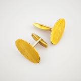 Paar ovale Manschettenknöpfe aus Gelbgold mit glatter Struktur und poliertem Schimmer auf weißem Hintergrund