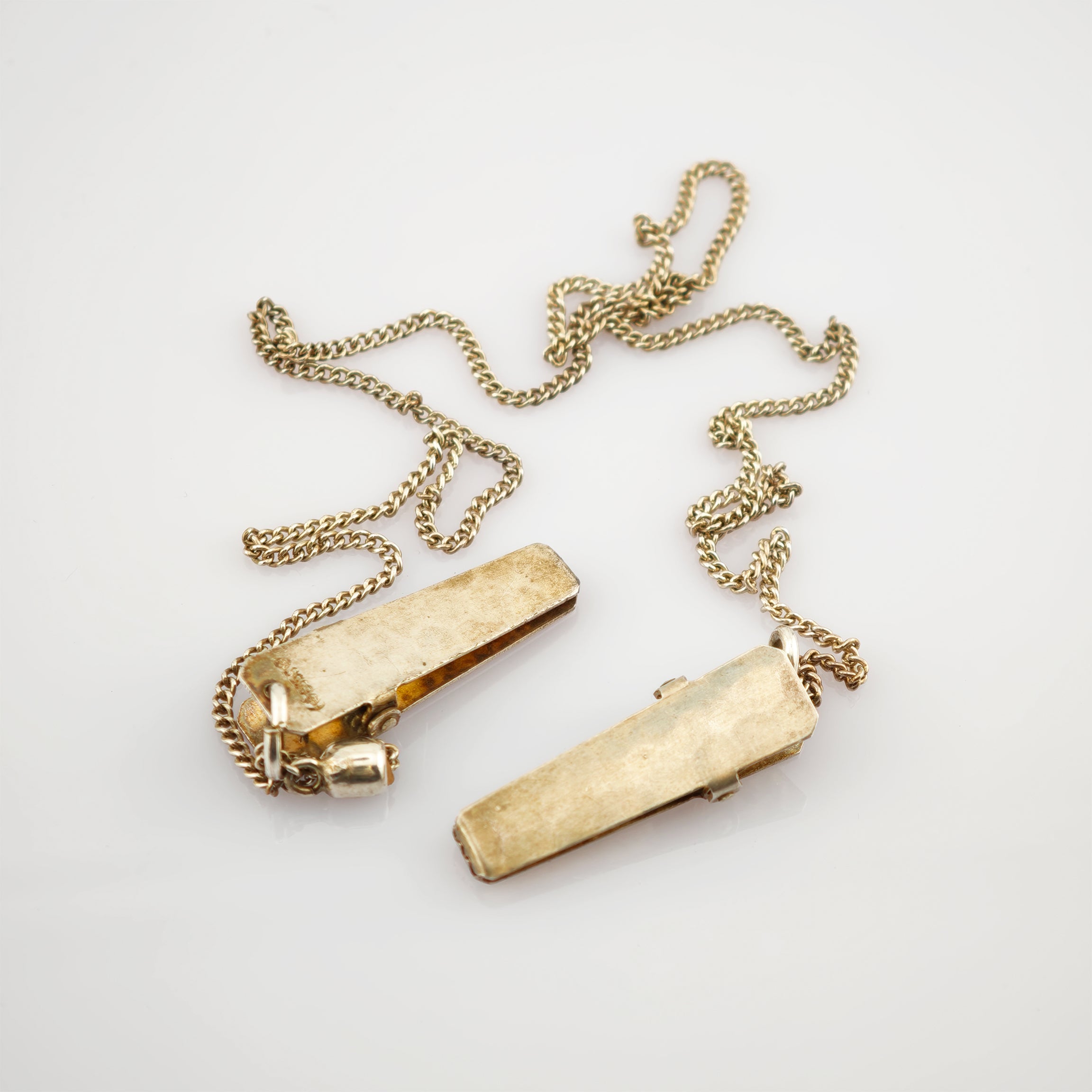 Paar vintage goldfarbene Manschettenknöpfe mit feinen verdrehten Ketten auf weißem Hintergrund