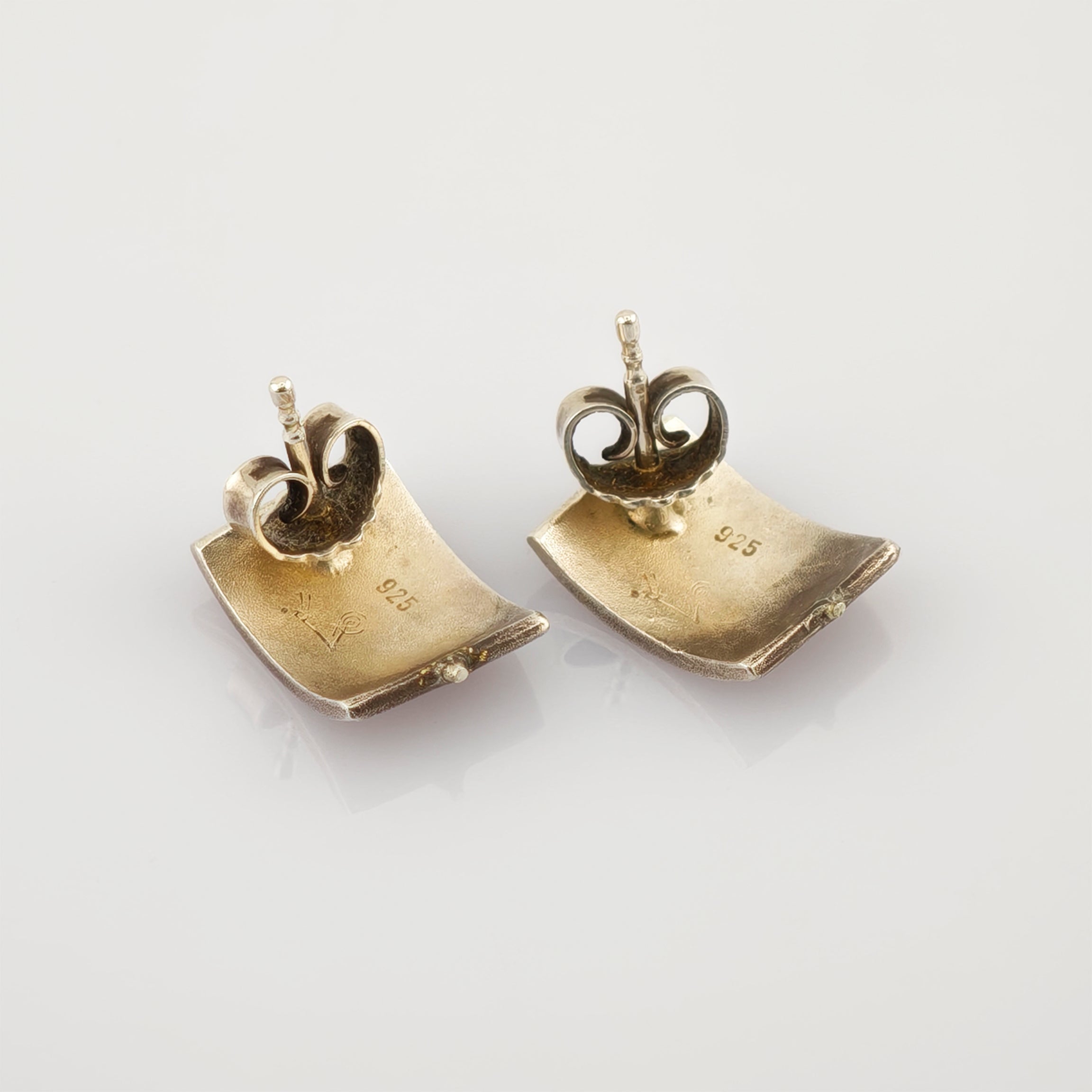 Paar quadratische, strukturierte Silberohrringe mit 925 Sterlingsilberpunze und Steckverschluss auf weißem Hintergrund.