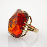 Ring mit facettiertem Bernstein in Goldfassung und breitem Band.