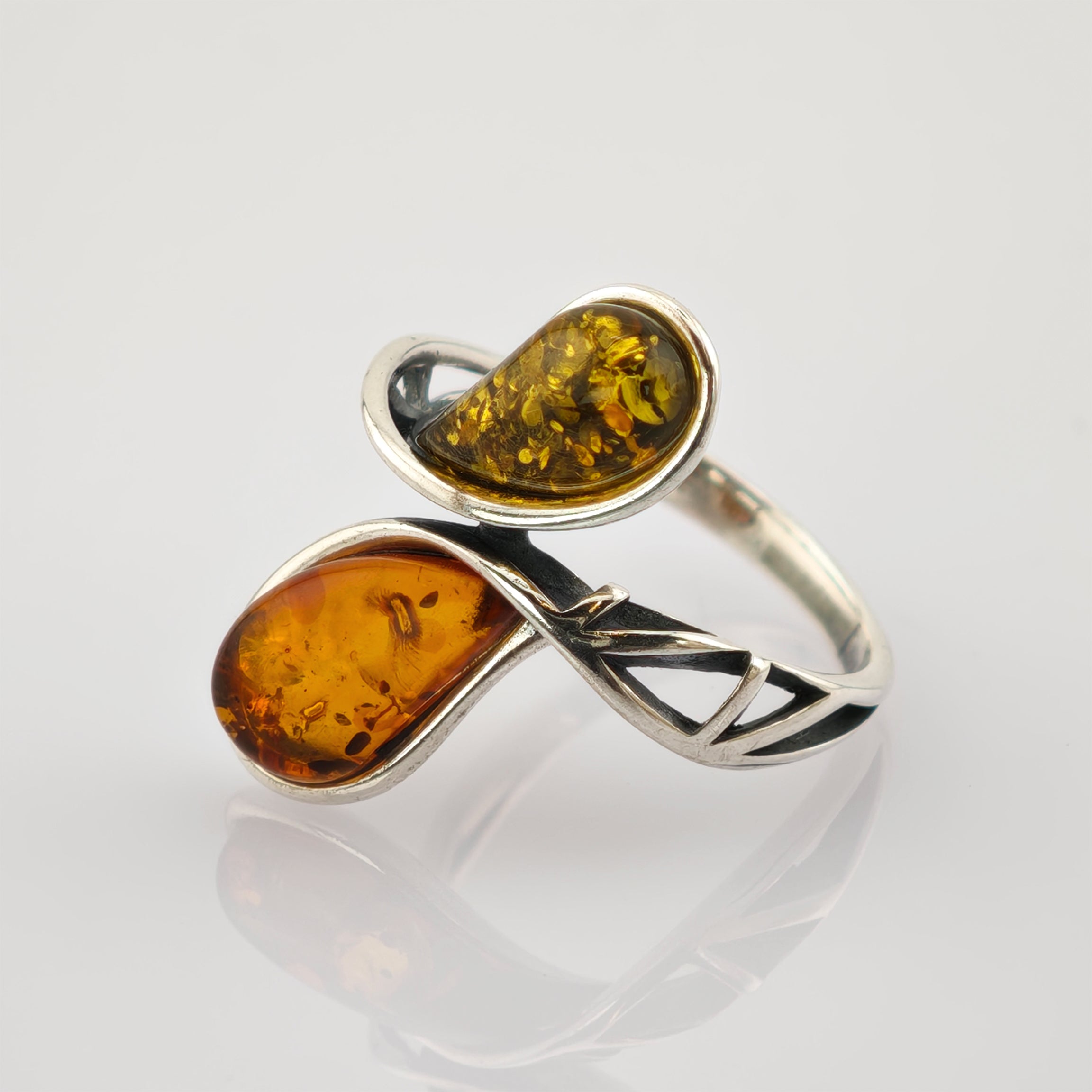 Silberring mit zwei Bernsteinen in Tropfenform auf gedrehtem Band mit dreieckigen Aussparungen.