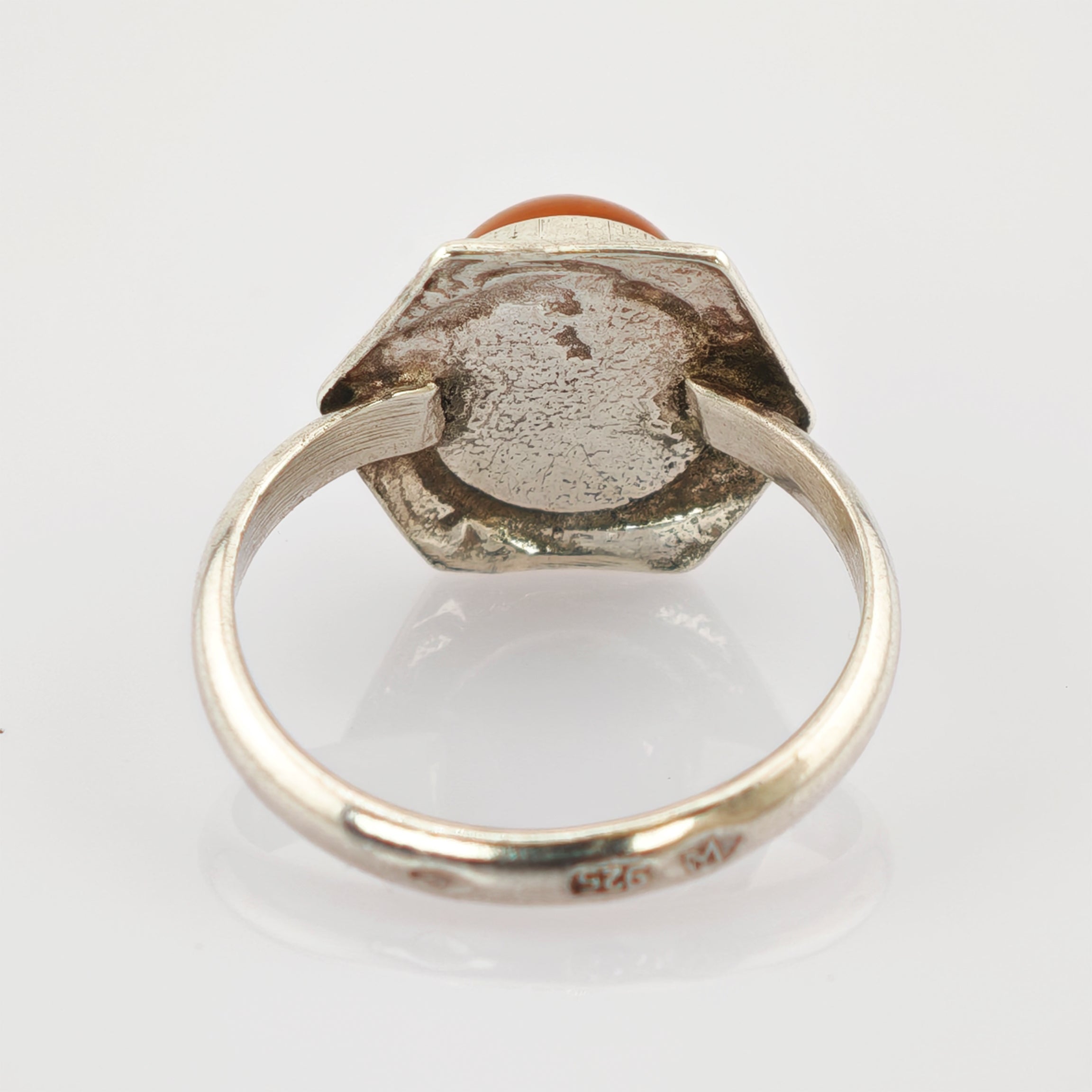 Rückansicht eines silbernen Rings mit achteckiger Fassung und teilweise sichtbarem roten Stein, innen Gravur 925 und M.