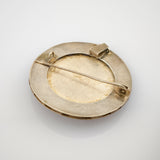 Rückseite einer runden Silberbroche mit Verschluss und 925-Punze auf weißem Hintergrund.