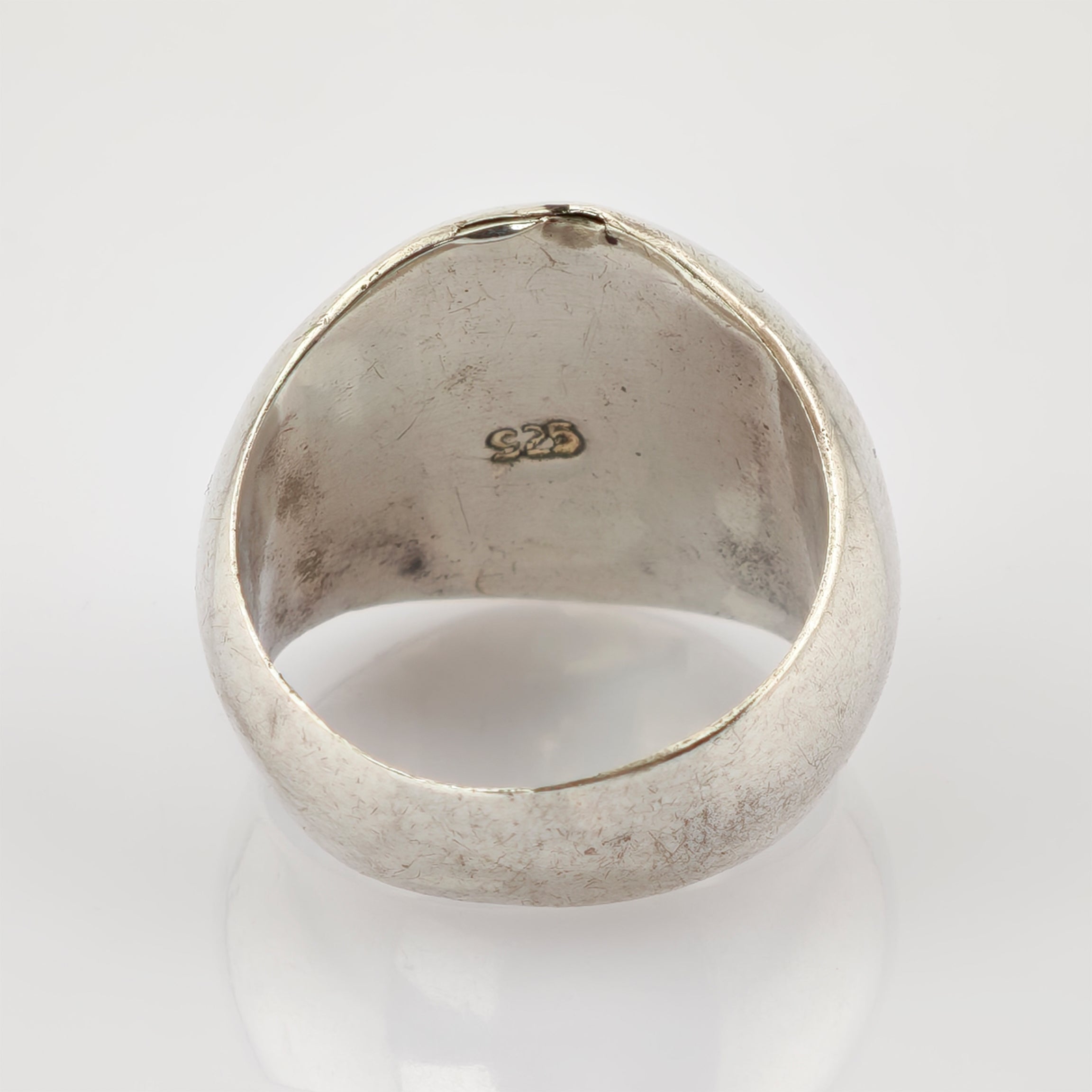 Reflektierender Metallring mit 925er-Silberpunze, abgenutzte Oberfläche und Kratzer vor hellgrauem Hintergrund