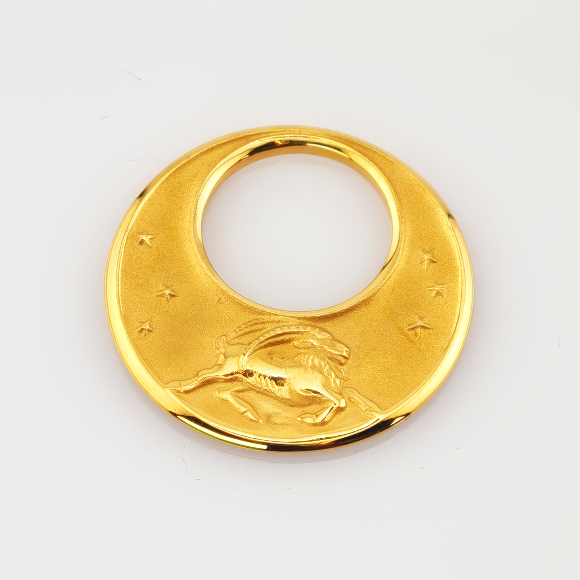 Runder goldener Anhänger mit zentralem Loch, geprägtem Steinbock und sechs Sternmotiven