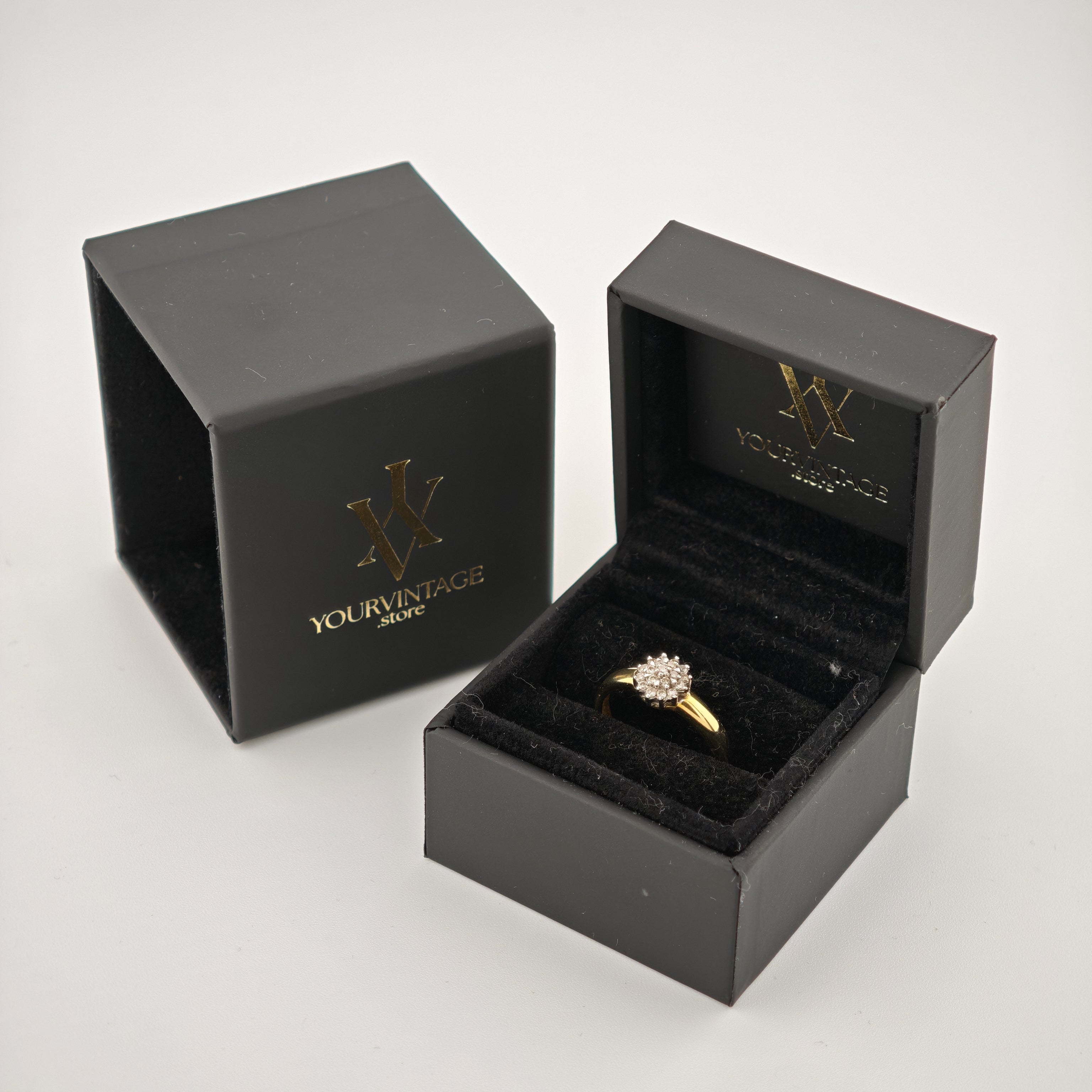 Schwarze Schmucketuis mit goldenem YOURVINTAGE Logo. Ein Etui offen mit Goldring und Diamanten auf schwarzem Samtkissen.