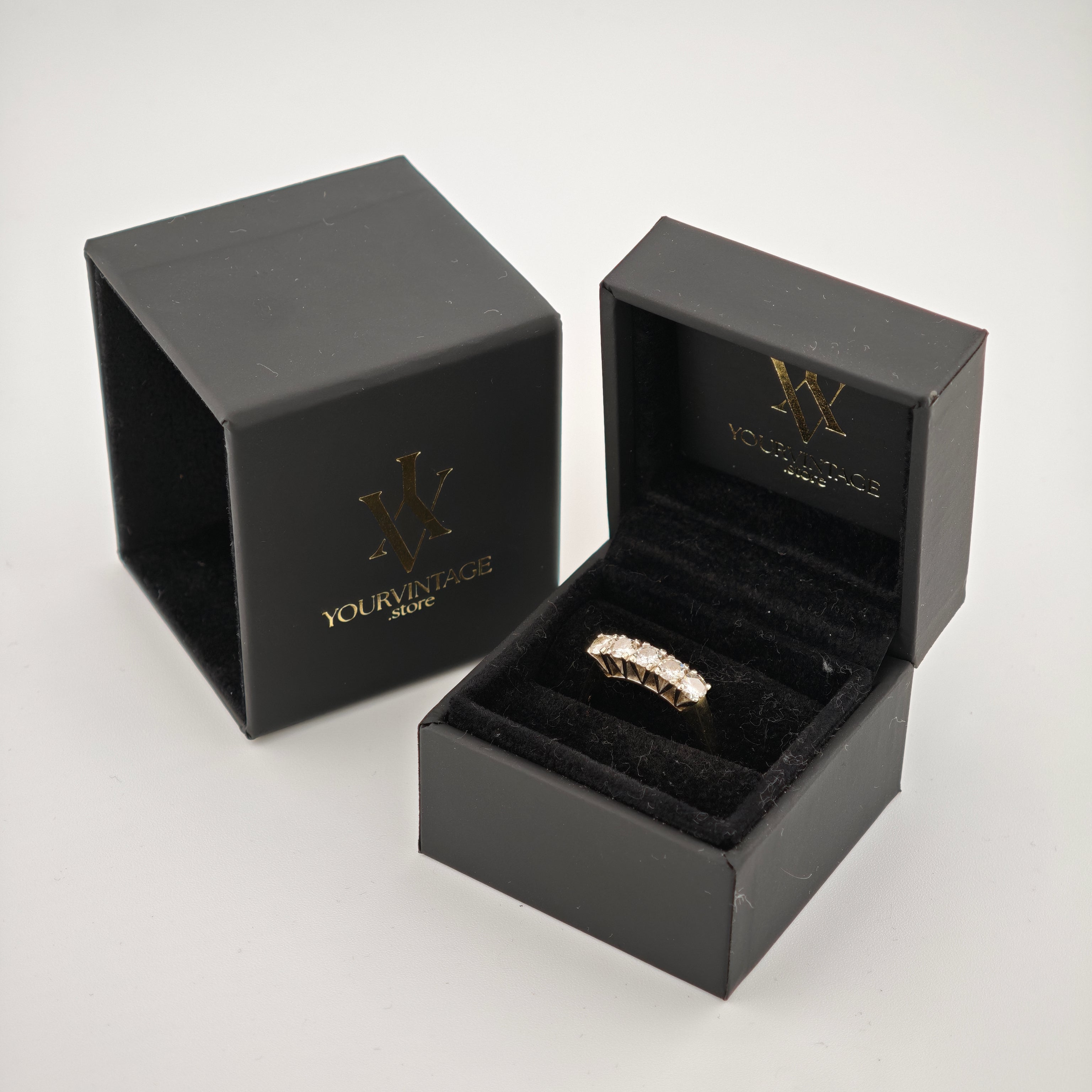 Geöffnete schwarze Schmuckbox mit goldfarbenem Ring und Diamanten auf schwarzem Samt, mit goldenem YOURVINTAGE.store Logo.