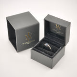 Schwarze Ringbox mit Samtfutter zeigt goldenen Ring mit dunklem Stein und zwei kleinen Seitsteinen, IhrVintage Store Logo.