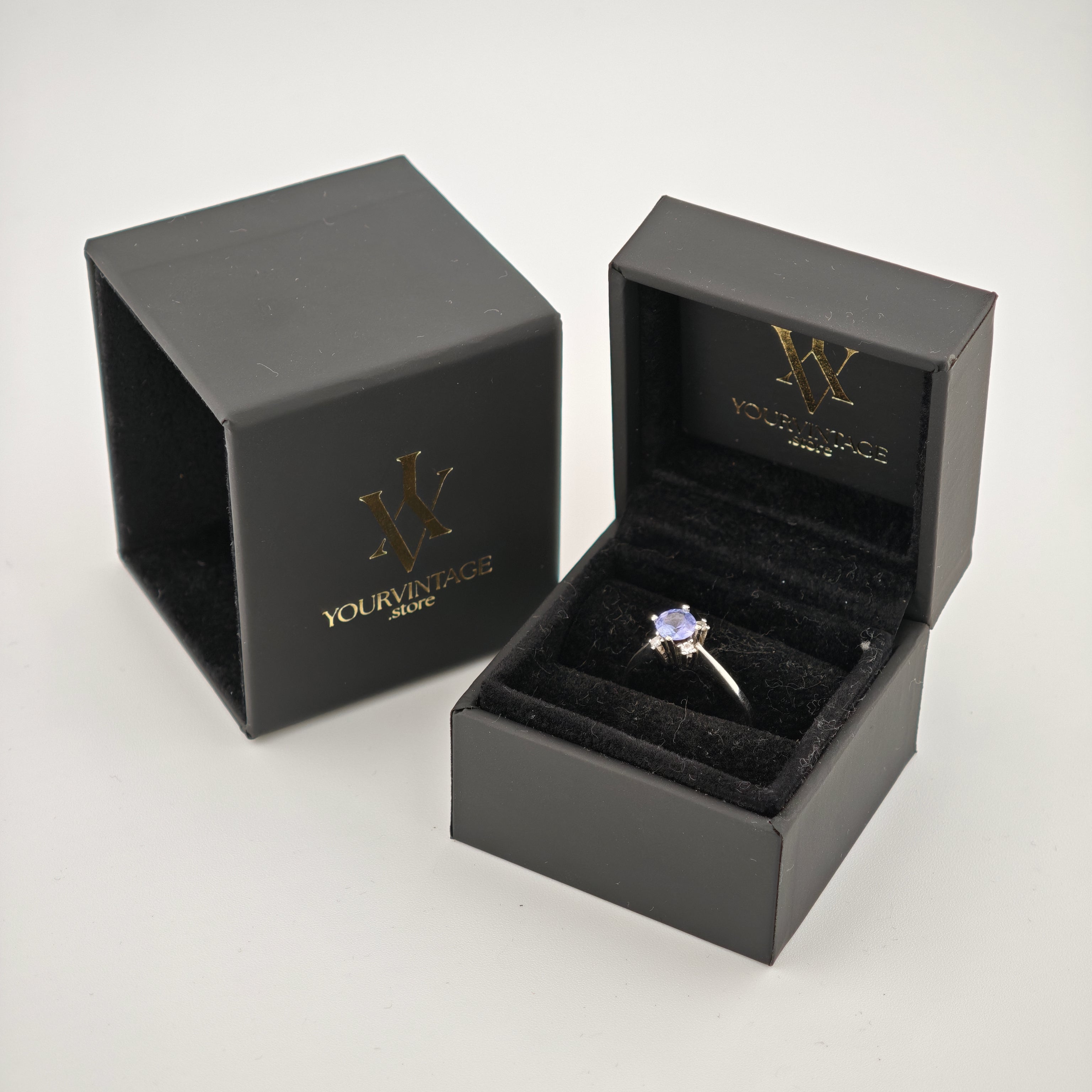 Schwarze Schmuckbox mit Silberring und violettem Edelstein auf schwarzem Samt mit Goldlogo von YourVintage Store.
