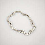 Silberarmband mit doppelter Kettenstruktur und fünf gleichmäßig verteilten schwarzen Steinen auf hellem Hintergrund.