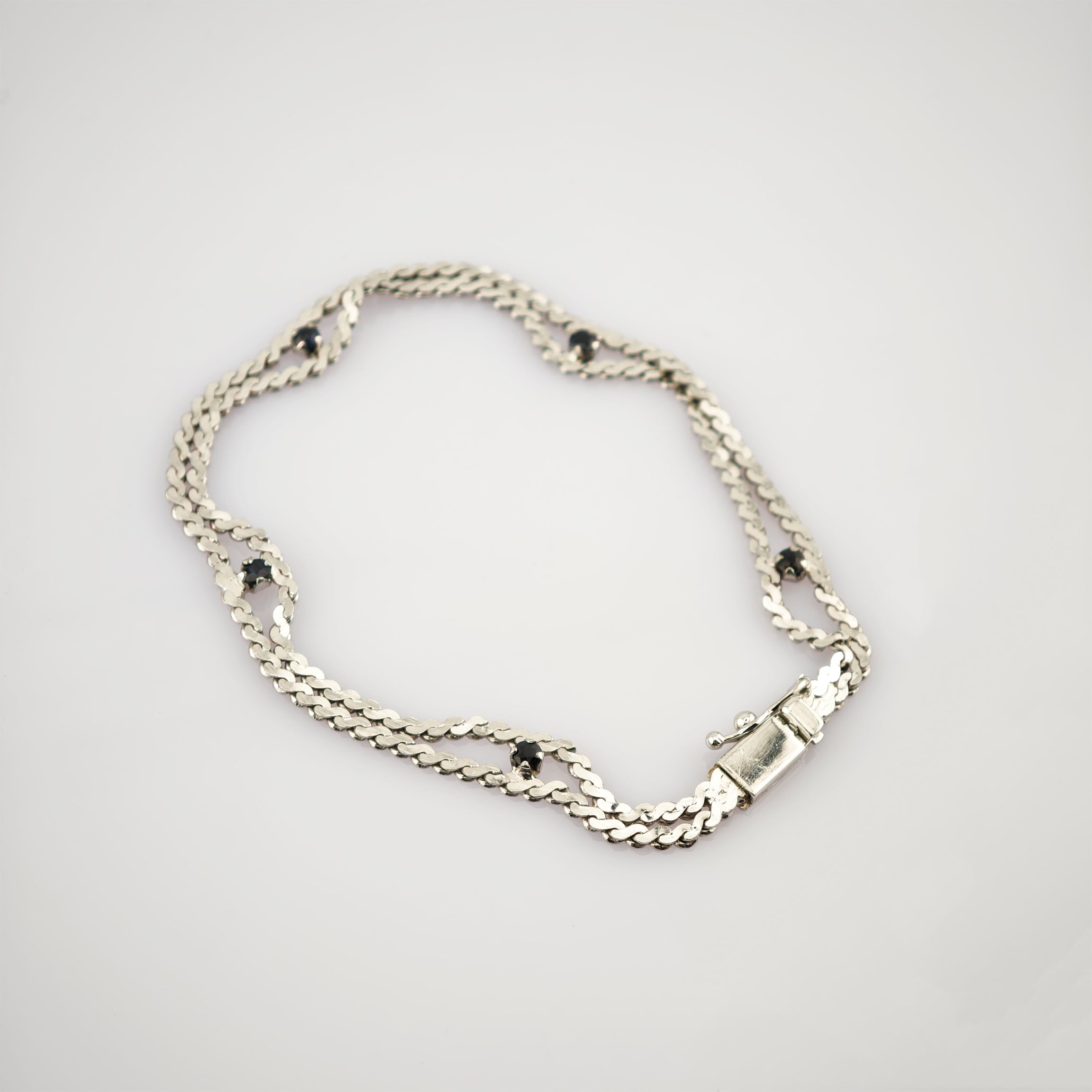 Silberarmband mit doppelter Kettenstruktur und fünf gleichmäßig verteilten schwarzen Steinen auf hellem Hintergrund.