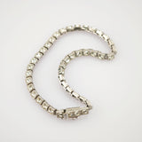 Silberarmband mit quadratischen Gliedern und funkelnden klaren Steinen auf weißem Hintergrund.