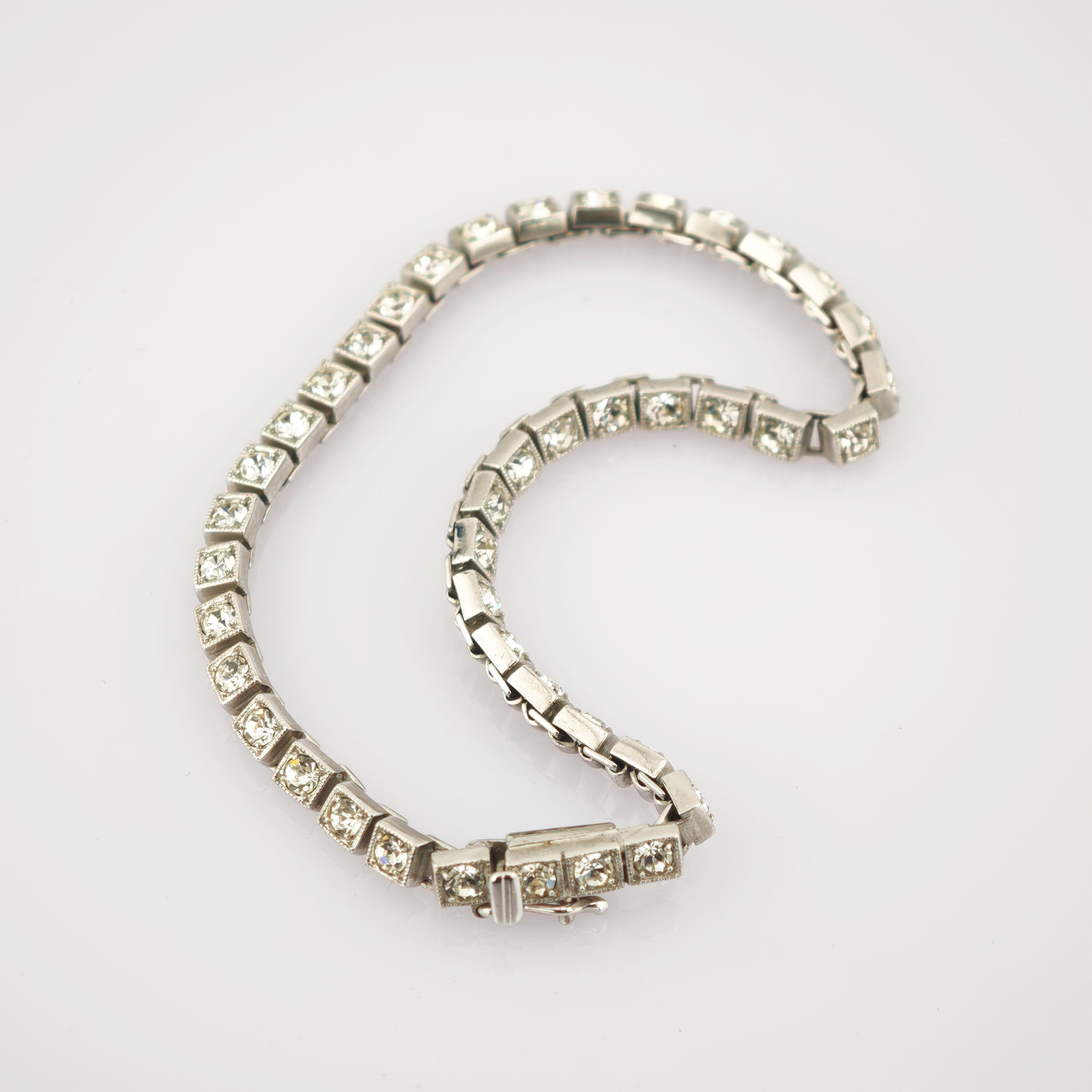 Silberarmband mit quadratischen Gliedern und funkelnden klaren Steinen auf weißem Hintergrund.