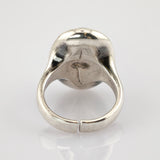 Silberfarbener Metallring mit offenem, verstellbarem Band und sichtbaren Gebrauchsspuren vor weißem Hintergrund.