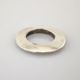 Silberne, abgenutzte Metallscheibe mit Loch in der Mitte auf hellem Hintergrund