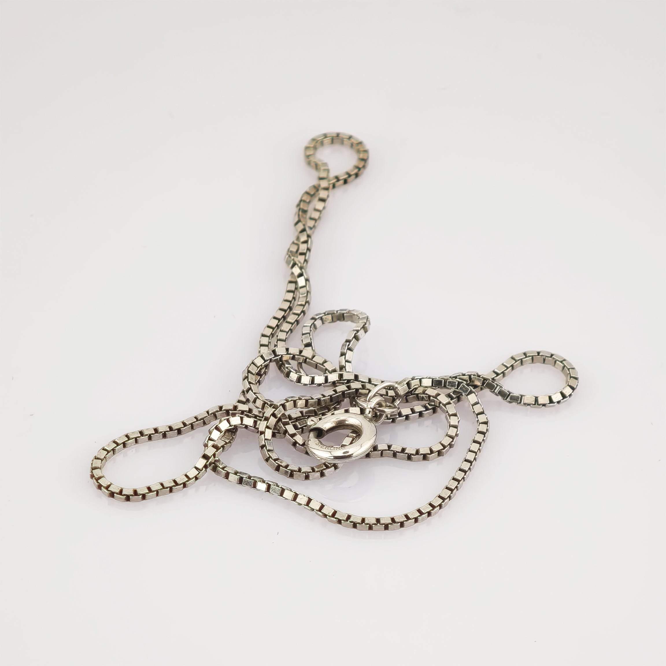 Silberne Halskette mit Kastengliederkette und rundem Verschluss mit Sterling-Gravur auf weißem Hintergrund.