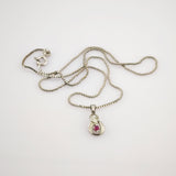 Silberne Halskette mit Kastenkettenmuster und geschwungenem Anhänger mit rotem Rubin.