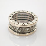 Silberner Bvlgari-Ring mit eingraviertem Markennamen und kleinen Diamanten auf reflektierender Oberfläche.