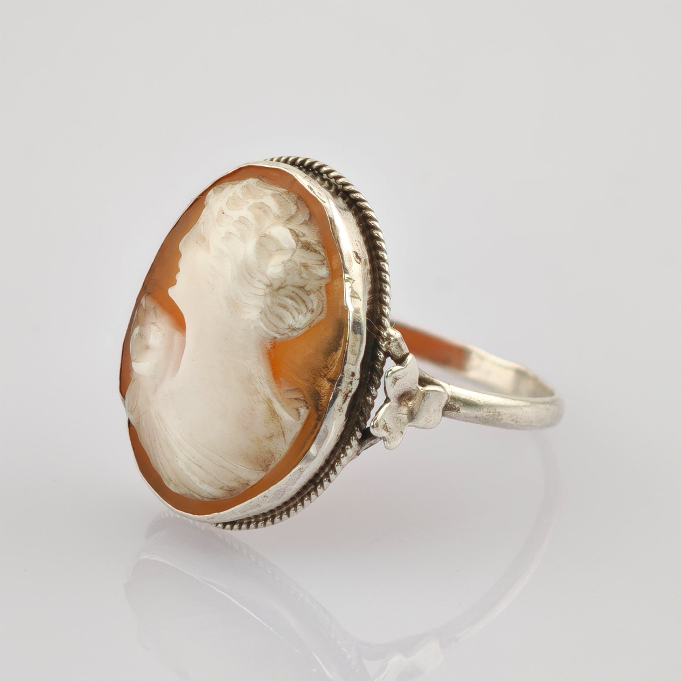 Silberner Kamee-Ring mit geschnitztem Frauenprofil auf bernsteinfarbenem Hintergrund.