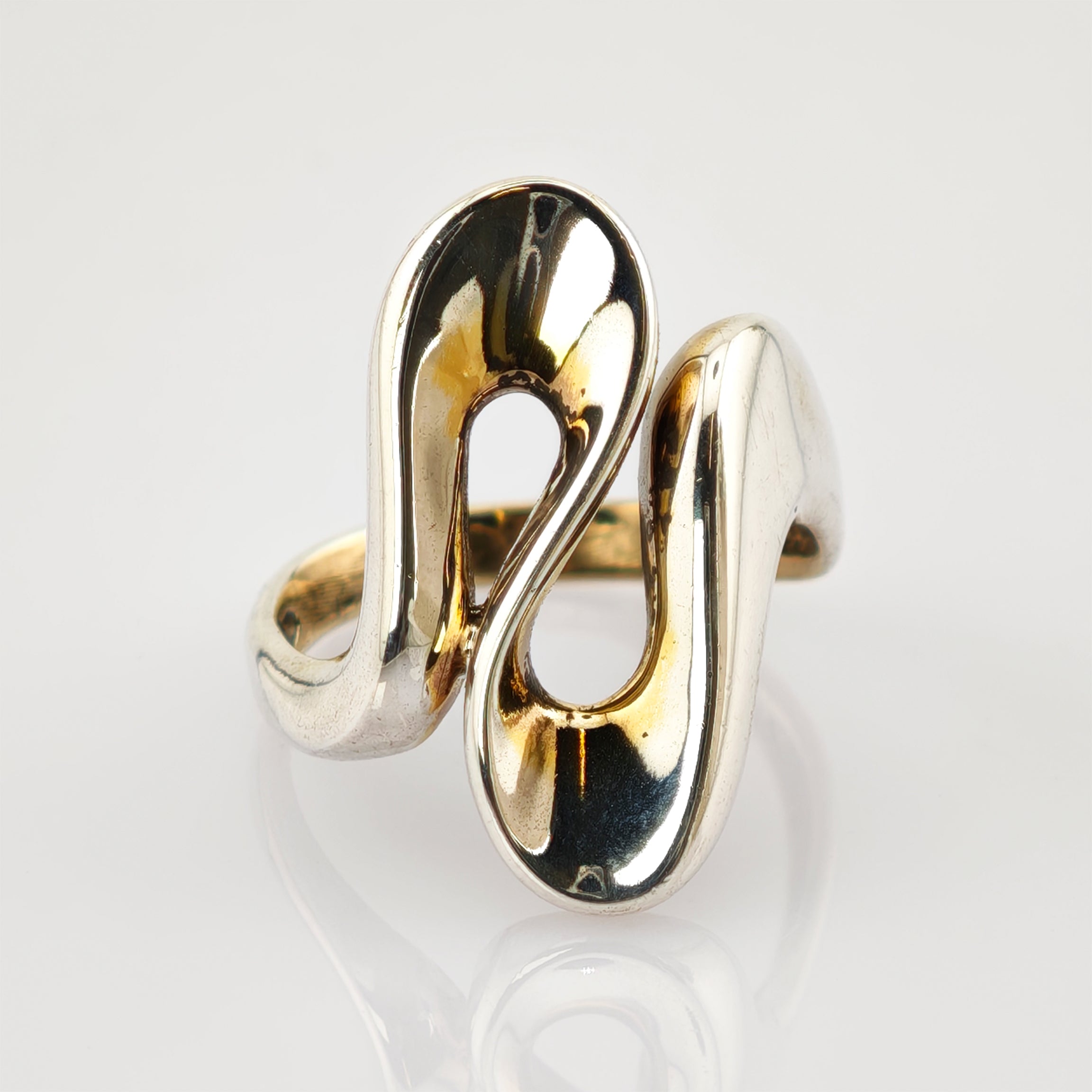 Silberner moderner Ring mit symmetrischen Elementen und polierter Oberfläche vor hellem Hintergrund