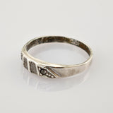 Silberner Ring mit antikem Finish, strukturierte Elemente und kreisförmige Details auf weißem Hintergrund