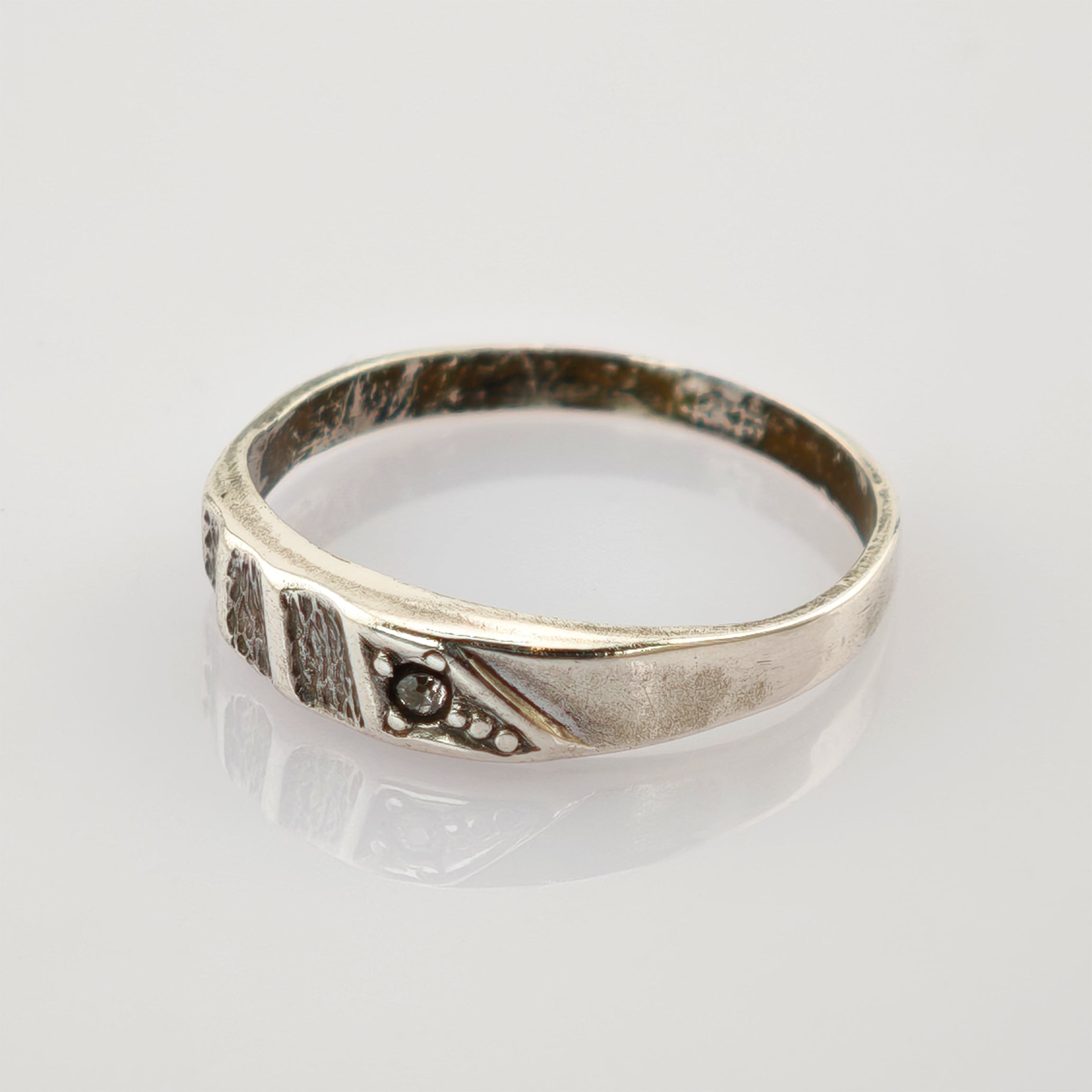 Silberner Ring mit antikem Finish, strukturierte Elemente und kreisförmige Details auf weißem Hintergrund