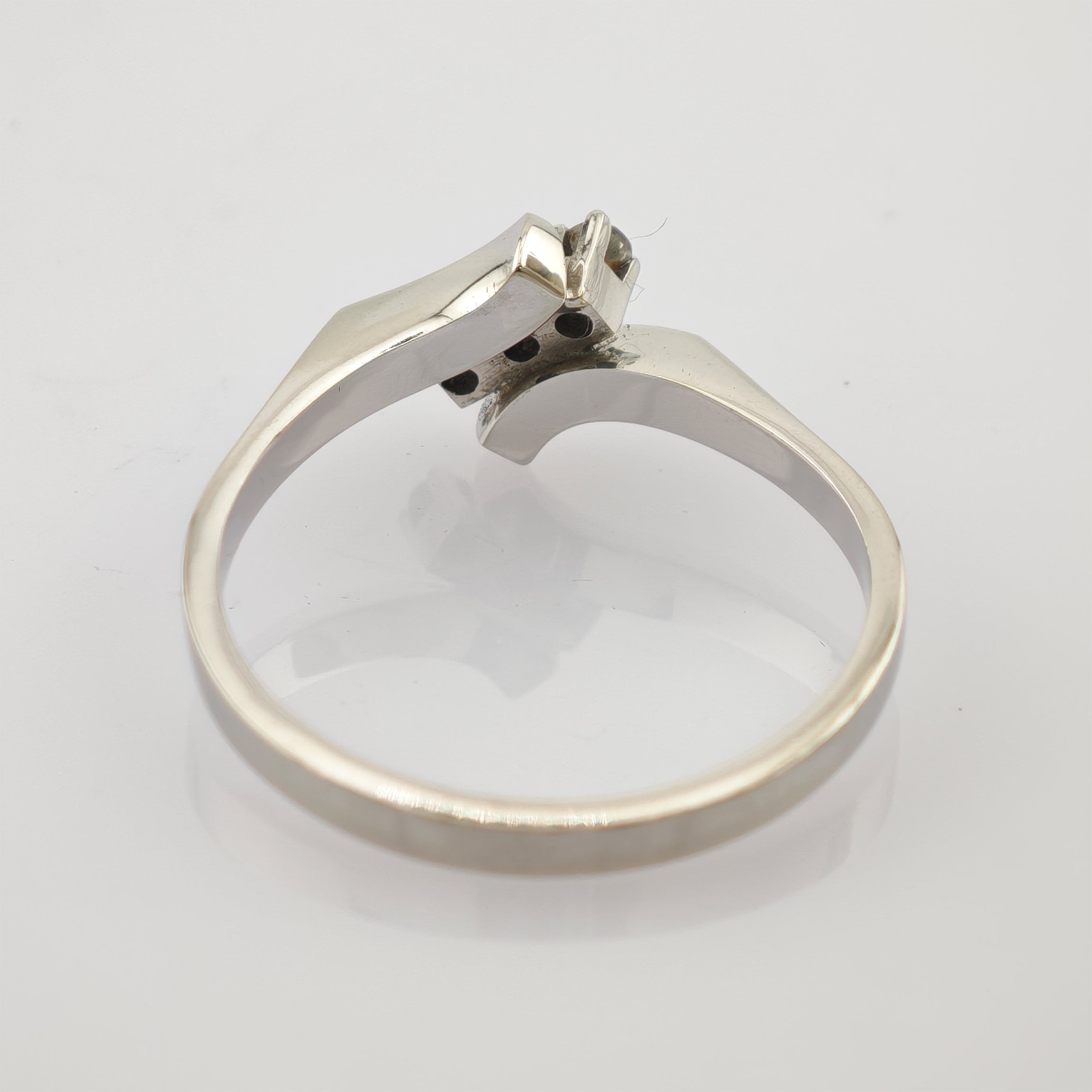 Silberner Ring mit asymmetrischem Band und rechteckiger Fassung auf reflektierendem Hintergrund.