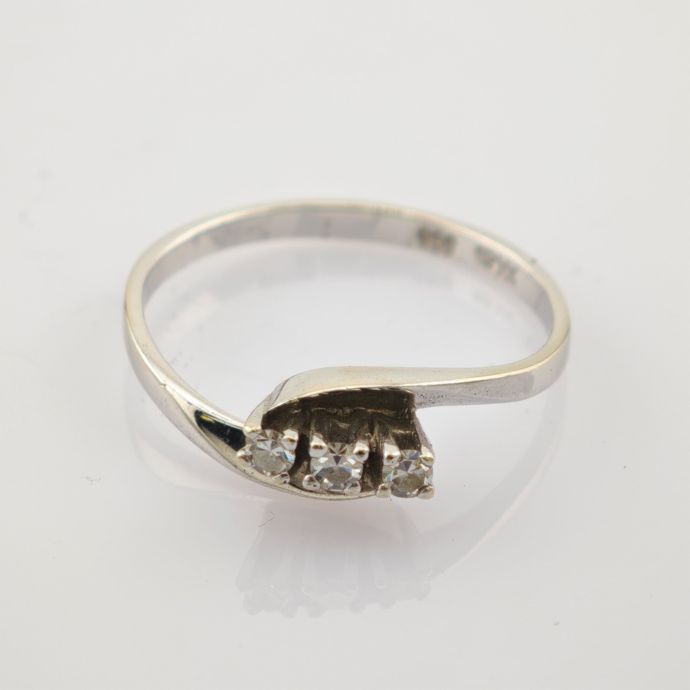 Eleganter silberner Ring mit gedrehter Bandschleife und drei kleinen runden Diamanten, innen mit 925 Sterling Punze.