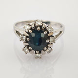 Silberner Ring mit großem facettiertem dunkelblauem ovalem Stein und klaren runden Steinen im Sonnenmuster.