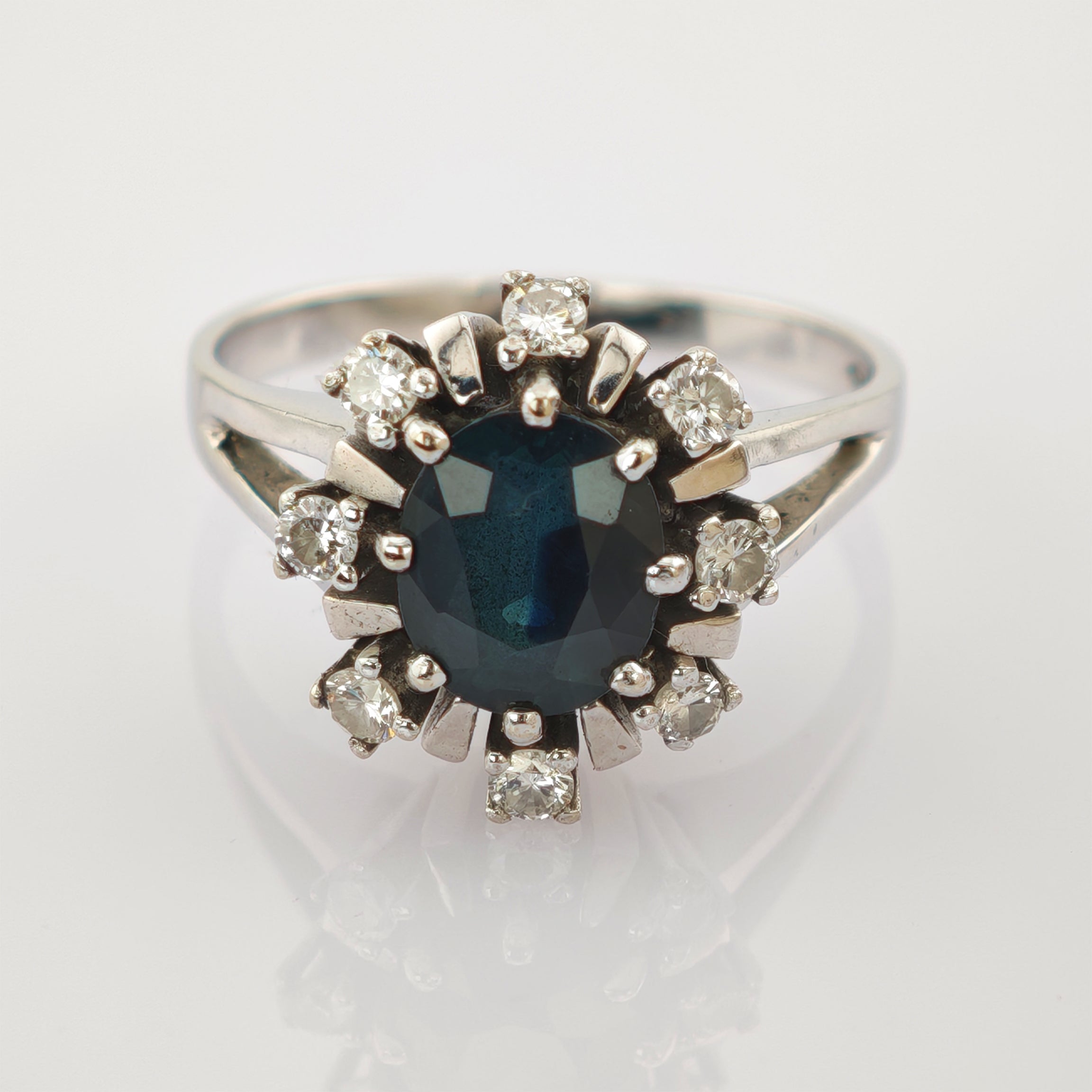 Silberner Ring mit großem facettiertem dunkelblauem ovalem Stein und klaren runden Steinen im Sonnenmuster.