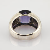 Silberner Ring mit facettiertem dunkelviolettem Edelstein und breitem Band mit leichten Gebrauchsspuren.