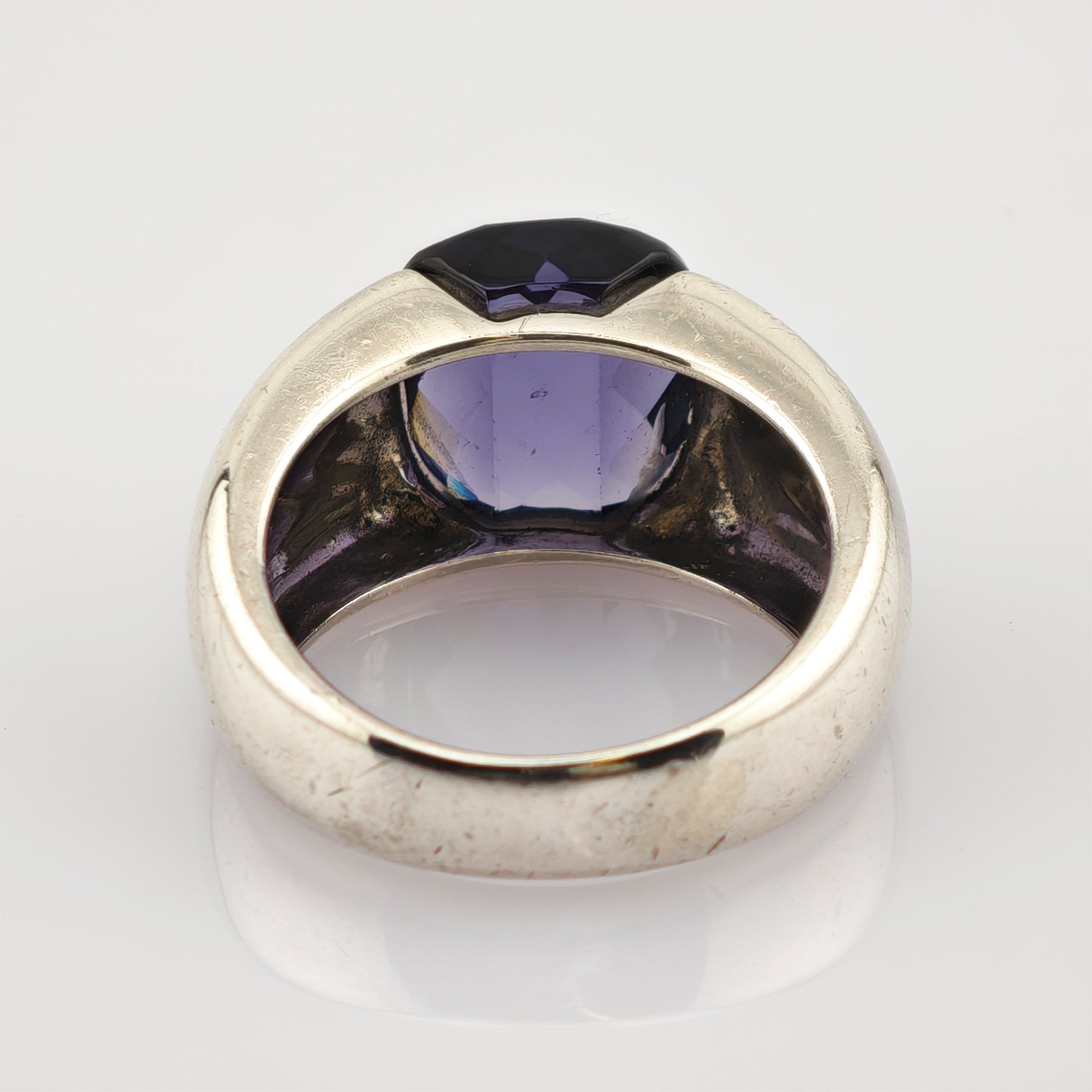 Silberner Ring mit facettiertem dunkelviolettem Edelstein und breitem Band mit leichten Gebrauchsspuren.
