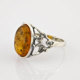 Silberner Ring mit filigranem Schnittmuster und großem ovalem Bernstein mit natürlichen Einschlüssen