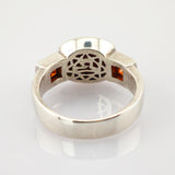 Silberner Ring mit filigranen Mustern und zwei kleinen quadratischen orangen Edelsteinen an den Seiten