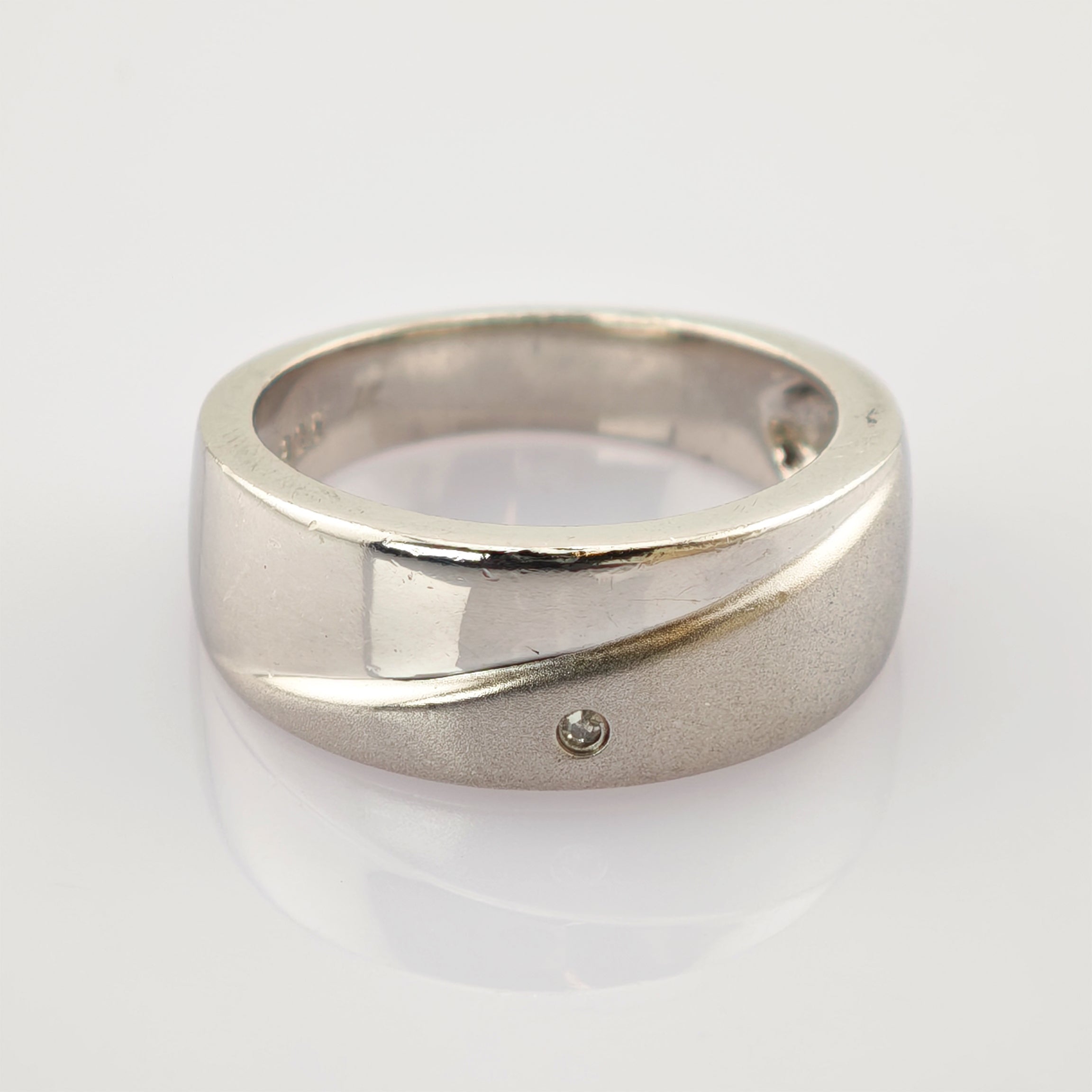 Silberner Ring mit glatter Oberfläche und diagonaler Linie auf weißem Hintergrund