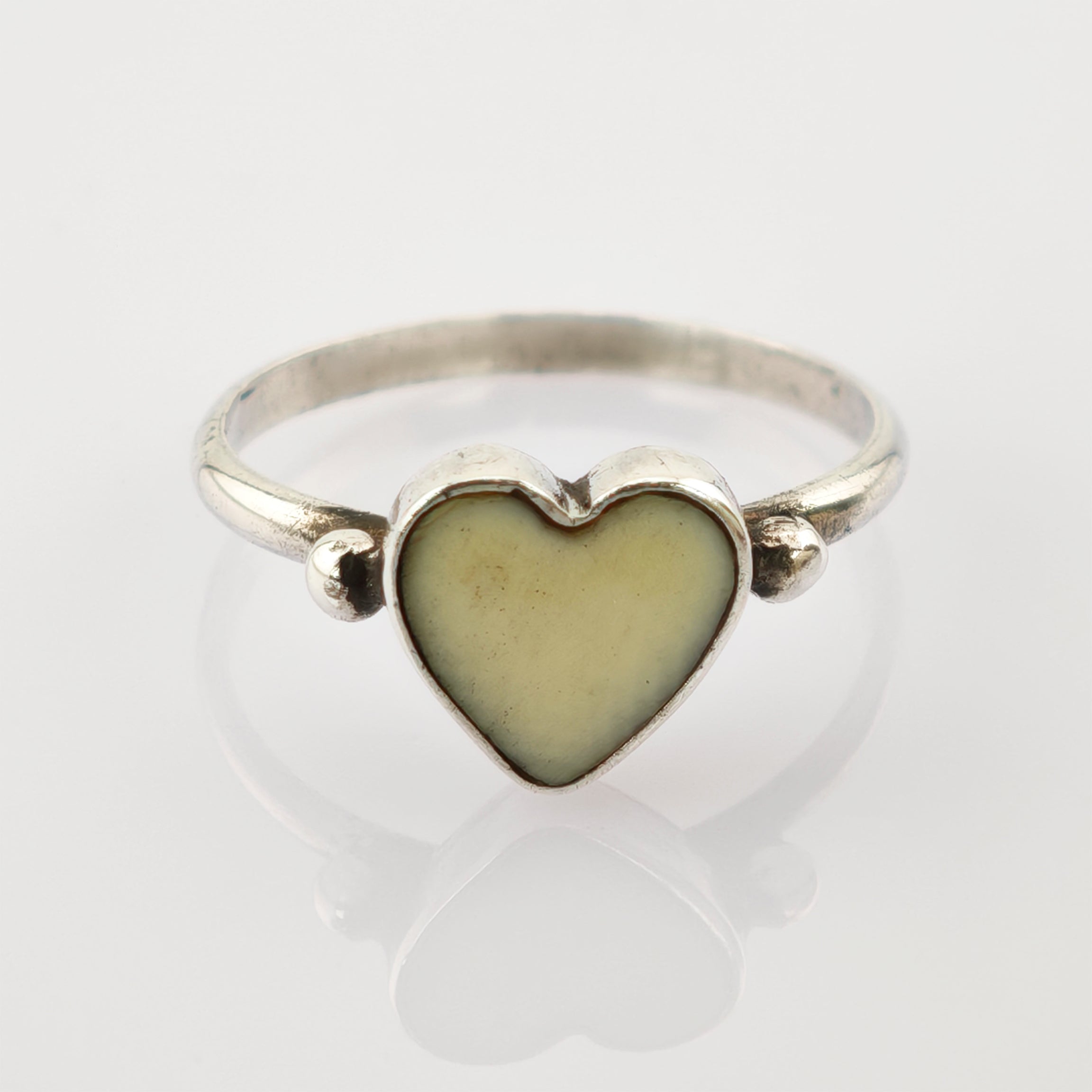 Silberner Ring mit herzförmigem gelbem Zentrum und silbernen Perlendetails auf weißem Hintergrund